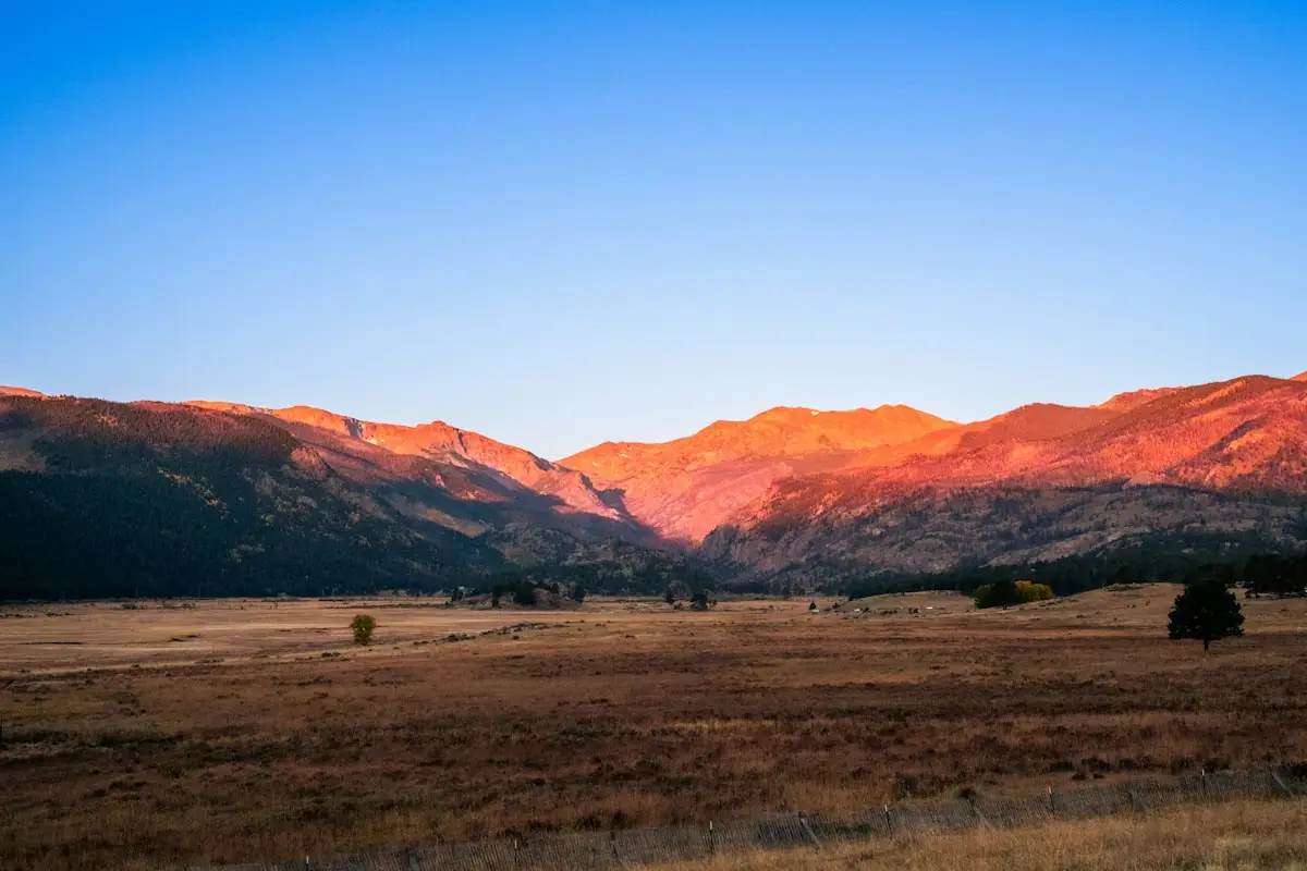 Campo aberto com montanhas iluminadas pelo sol
